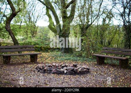 Stone fireplace photographed with a wooden bench in nature. Stock Photo