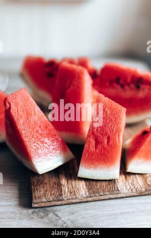 Ripe pieces of watermelon on a wooden cutting board in the kitchen. Vertical photo orientation. Food Backrgound. Stock Photo