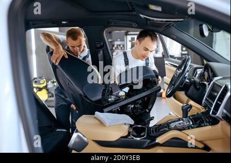 Two workers removes car seats for detailing Stock Photo