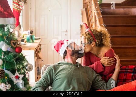 Kiss and love with adult couple during christmas holiday season time at home - concept of life together and happiness at 40s and 50s years old - happy Stock Photo