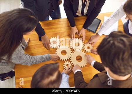 Startup team joining cogwheels as metaphor for teamwork, management and finding business solutions Stock Photo