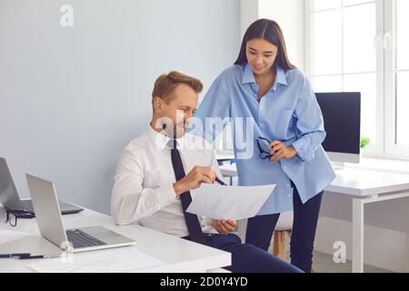 Company workers discussing financial report and sharing work ideas in cozy modern office Stock Photo