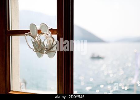 Bridal sandals on a wooden window frame overlooking the sea. Stock Photo