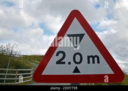 Two metre height restriction sign in red warning triangle with blurred barrier in background. Isle of Skye, Scotland, UK. Stock Photo