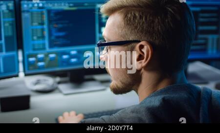 IT Specialist Works on Personal Computer with Screens Showing Software Program with Coding Language Interface. In the Background Technical Room of Stock Photo