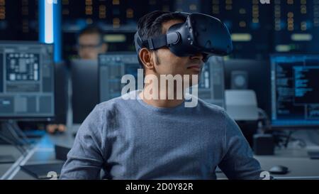 Software Delevoper Wearing Virtual Reality Headset on His Head, Developing and Programming VR Game or Application. In the Background Technology Stock Photo