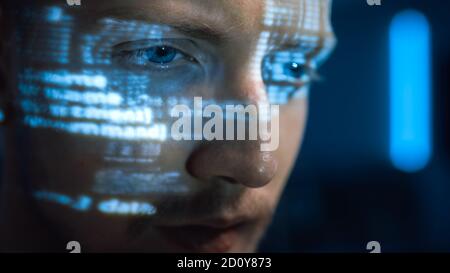 Portrait of Software Developer Hacker Working on Personal Computer, Projected Code Numbers and Characters Reflect on His Face. Dark Room Full of Stock Photo