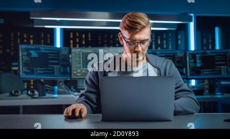 Portrait of Software Developer Hacker Wearing Glasses Sitting at His Desk and Working on Computer in Digital Identity Cyber Security Data Center Stock Photo
