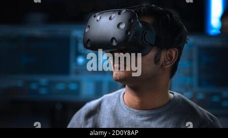 Software Delevoper Wearing Virtual Reality Headset on His Head, Developing and Programming VR Game or Application. In the Background Technology Stock Photo