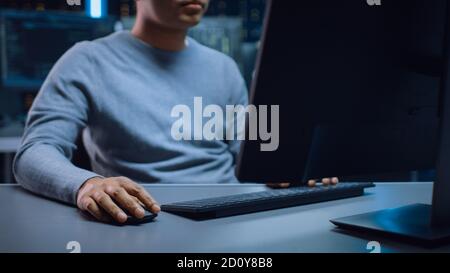 Portrait Shot of Anonymous Software Developer Sitting at His Desk and Working on Computer in Digital Identity Cyber Security Data Center. Hacking or Stock Photo