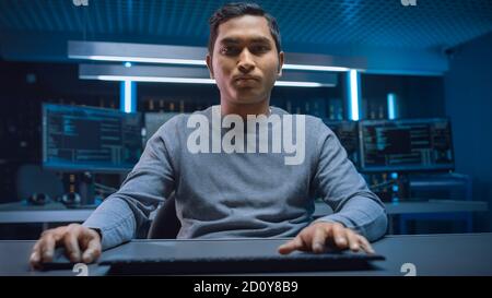 Portrait of Software Programmer Sitting at His Desk and Working on Computer in Digital Identity Cyber Security Data Center. Hacking or Programming. Stock Photo