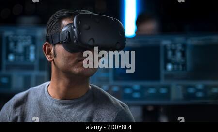 Software Delevoper Wearing Virtual Reality Headset on His Head, Developing and Programming VR Game or Application. In the Background Technology Stock Photo