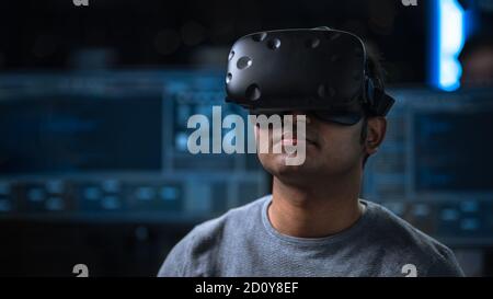Software Delevoper Wearing Virtual Reality Headset on His Head, Developing and Programming VR Game or Application. In the Background Technology Stock Photo