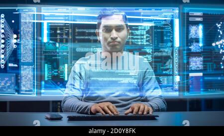 Portrait of Software Developer Hacker Wearing Glasses Sitting at His Desk and Working on Futuristic Transparent Computer in Digital Identity Cyber Stock Photo