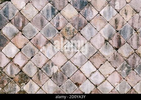Sidewalk paving stones with a diamond shape from a natural stone of gray color close-up. Stock Photo