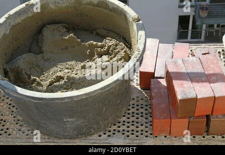 bricks and mortar bucket on scaffolding Stock Photo