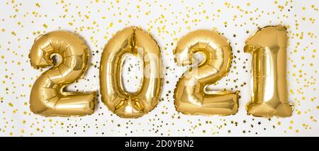 Golden 2021 balloons. Gold metallic foil numbers for Happy New Year celebration on white background with glitter confetti stars. Helium balloon as hol Stock Photo