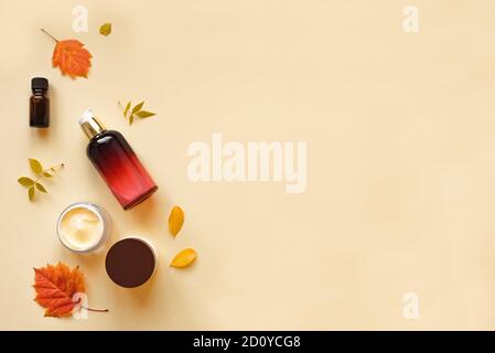 Autumn Skin Care products and autumn leaves on yellow background, flat lay, copy space.  Seasonal beauty routine and organic cosmetic concept. Stock Photo