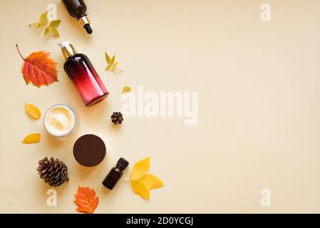 Autumn Skin Care products and autumn leaves on yellow background, flat lay, copy space.  Seasonal beauty routine and organic cosmetic concept. Stock Photo