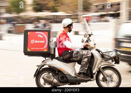 Belgrade, Serbia - October 02, 2020: Courier working for Donesi city food delivery service riding a scooter motorbike in city street Stock Photo
