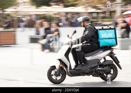 Belgrade, Serbia - October 02, 2020: Courier working for Wolt city food delivery service riding a scooter motorbike in city street Stock Photo