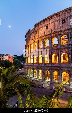 Section of the illuminated Roman Colosseum in rome during the blue hour in the early evening with the moon shinning down in a clear sky. Stock Photo