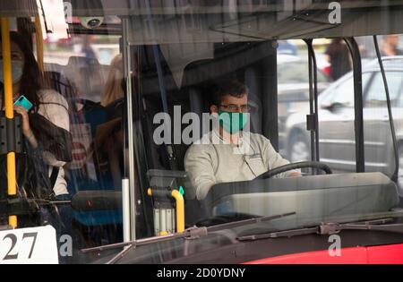 Belgrade, Serbia - October 02, 2020: Driver wearing face surgical mask driving a city bus with passengers, from outside through front glass Stock Photo
