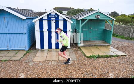 Worthing UK 4th October 2020 -  Runners in the Virtual London Marathon battle against the elements on a wet and windy day along Ferring seafront near Worthing as they reach their 20 mile mark : Credit Simon Dack / Alamy Live News Stock Photo