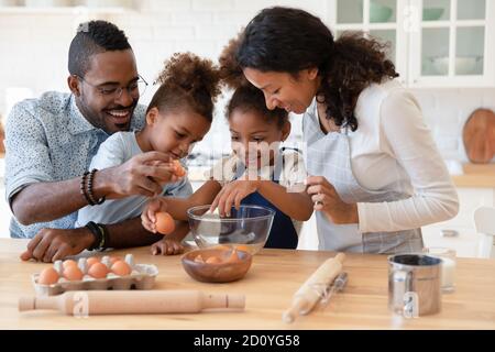 Smiling biracial little children involved in preparing breakfast with parents. Stock Photo