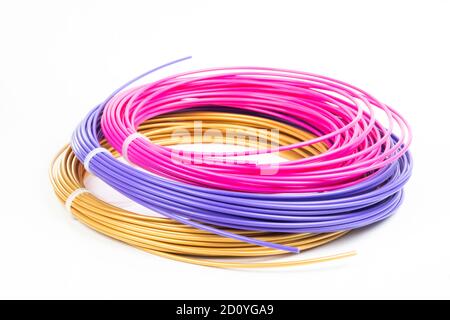Top view of of three colorful rolled filament 3D pen PLA isolated on white. Closeup of plastic bright wires for 3D printer lying indoors. Concept of c Stock Photo