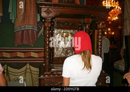 Bucharest, Romania.The 18th century Christian Orthodox St. Spyridon church. Woman praying in front of the icon and the relics of the patron saint. Stock Photo