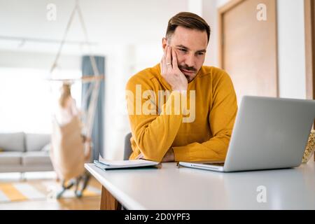 Upset young man counts family budget on laptop