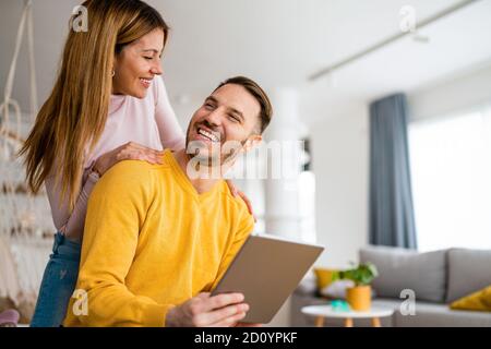 Couple in love hugging and using tablet together. Stock Photo
