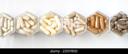 Various herbal and homeopathic medical capsules in hexagonal jars in the form of honeycomb Stock Photo