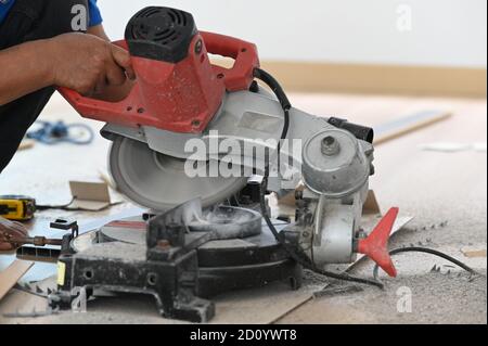 Skilled carpenter cutting a piece of wood in his woodwork workshop using a circular saw on wooden table. Stock Photo