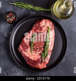 Fresh raw beef steak on black plate, top view. Stock Photo