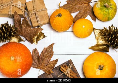 Hands with small decorative pumpkins. Pumpkins, autumn leafs, golden fir cones and gifts in craft paper. Holliday decoration concept design. Stock Photo