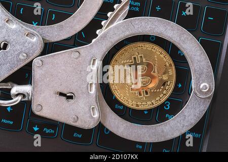 Handcuffs and bitcoin on a laptop keyboard, top view. Concept on the topic of punishment for mining digital currency Stock Photo