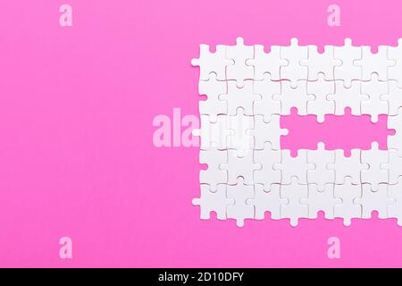 White jigsaw puzzle with empty space for text and pink background - Image Stock Photo