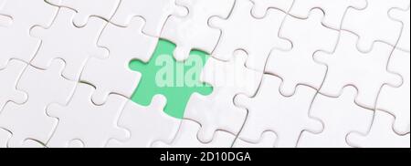 White jigsaw puzzle with with one piece missing and green background - Image Stock Photo