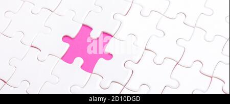 White jigsaw puzzle with with one piece missing and pink background - Image Stock Photo