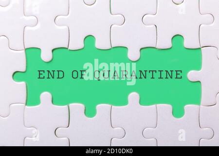 White puzzle background with pieces missing. Words END OF QUARANTINE. End of coronavirus and quarantine concept- Image Stock Photo