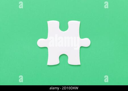 One white jigsaw puzzle piece on green background - Image Stock Photo