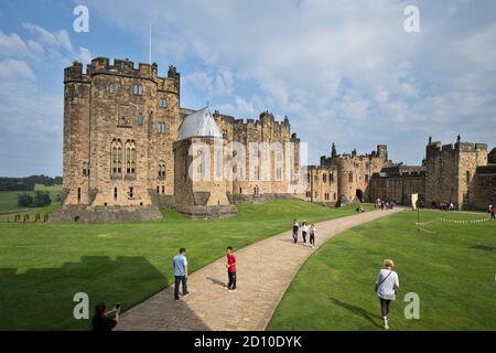 Tourists exploring the Outer Bailey of Alnwick Castle in Northumberland, a key location for Hogwarts in the Harry Potter films. Stock Photo