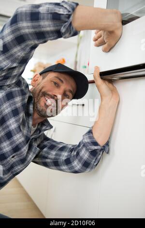 professional handyman in overalls repairing domestic oven Stock Photo