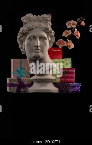 Statue of Apollo Belvedere, flowers and gifts boxes and packages, spotlights and multi-colored backgrounds. Stock Photo