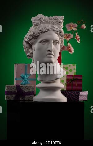 Statue of Apollo Belvedere, flowers and gifts boxes and packages, spotlights and multi-colored backgrounds. Stock Photo