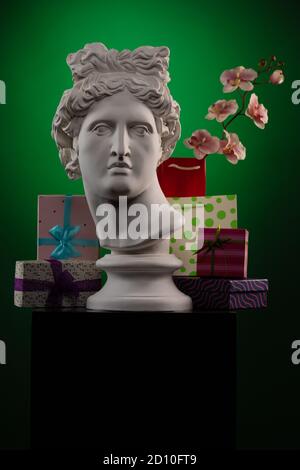 Statue of Apollo Belvedere, flowers and gifts boxes and packages, spotlights and multi-colored backgrounds. Stock Photo