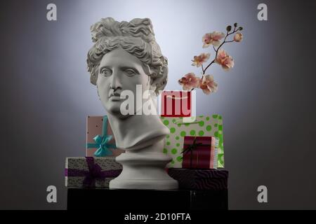 Statue of Apollo Belvedere, flowers and gifts boxes and packages, spotlights and multi-colored backgrounds. Stock Photo