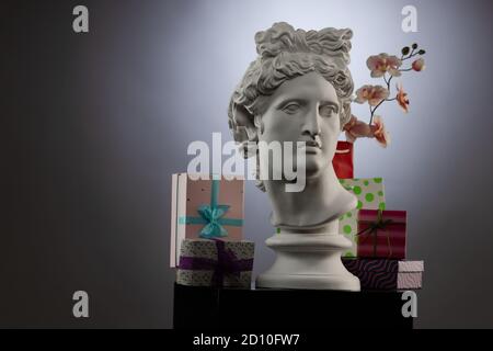 Statue of Apollo Belvedere, flowers and gifts boxes and packages, spotlights and multi-colored backgrounds. Stock Photo